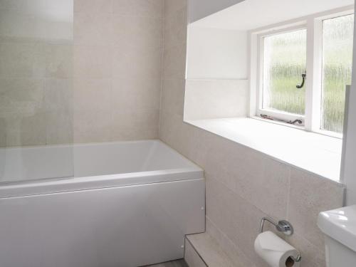 a white bathroom with a tub and a window at Hall Bank Cottage in Rydal