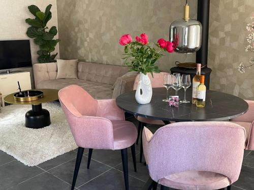 a living room with a table and pink chairs at Charmant, ontspannen Molenzicht in Ootmarsum