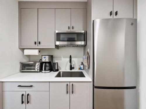 a white kitchen with a refrigerator and a microwave at Modern apartment near light rail in Seattle