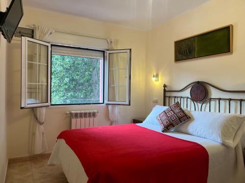 a bedroom with a red bed and a window at Hotel Alvaro frente Palacio-Museo Selgas in Cudillero