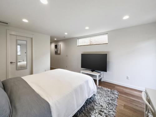 a bedroom with a large bed and a flat screen tv at Modern apartment near light rail in Seattle