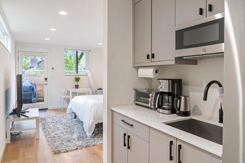 a kitchen with white cabinets and a sink and a bedroom at Modern apartment near light rail in Seattle