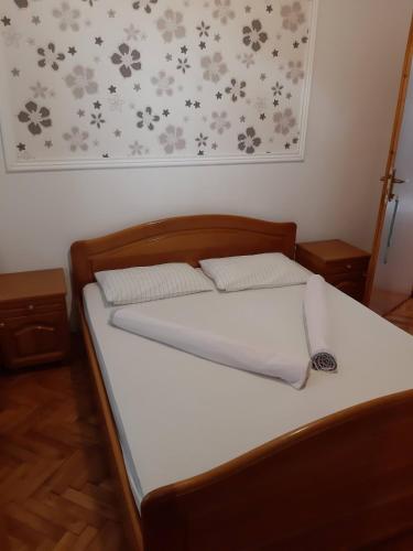 een slaapkamer met een bed met witte lakens en bloemen aan de muur bij Kalajdzic in Igalo