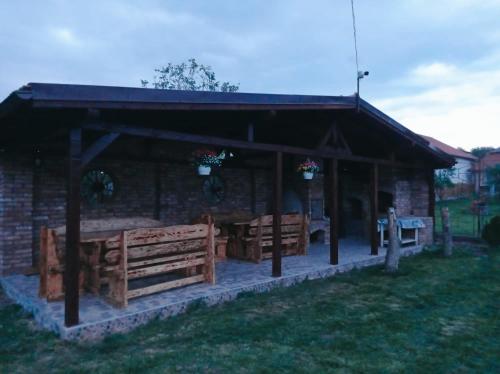 a pavilion with wooden benches and a building at Casa Vinco Vici in Turda
