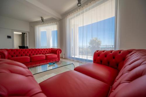 a living room with red couches and a large window at Villa Floyd Charming Rooms B&B in Pachino