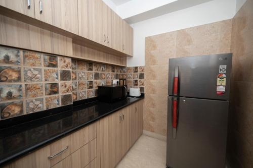 a kitchen with a stainless steel refrigerator and wooden cabinets at Lakeside Suites in Kolkata