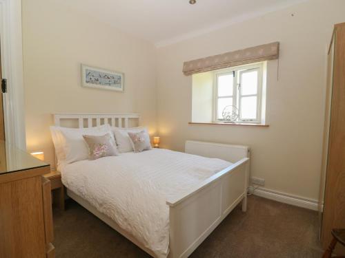 a bedroom with a white bed and a window at Ewecub Barn in Burford