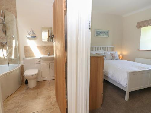 1 dormitorio con cama, bañera y lavamanos en Ewecub Barn, en Burford