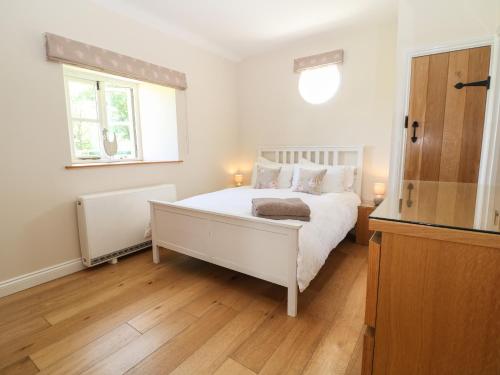 a bedroom with a white bed and a window at Nutchat Barn in Burford