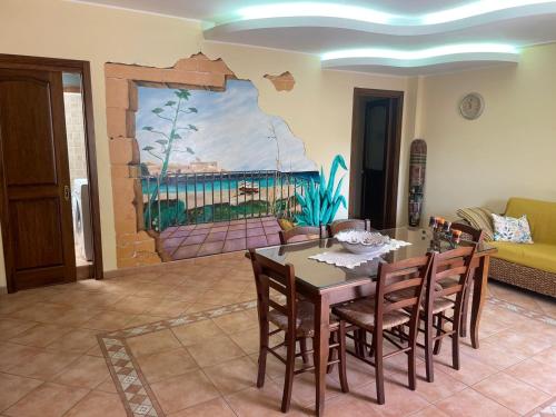 a dining room with a table and chairs and a painting at Don Concetto in Marzamemi