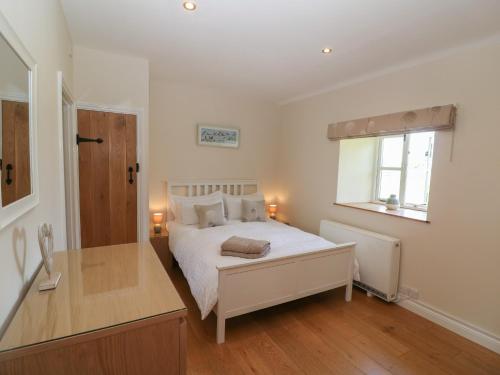 a bedroom with a bed with a desk and a window at Saddlebacks Barn in Burford