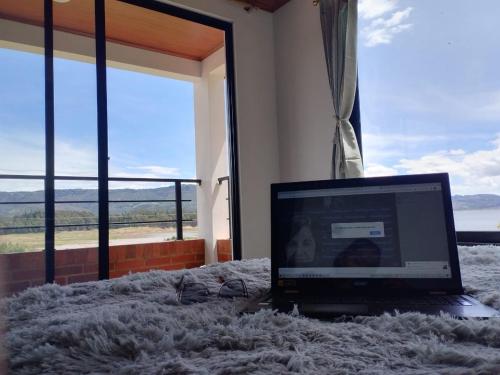 einen Laptop auf einem Bett in einem Zimmer mit Fenster in der Unterkunft Hotel Villa Blanca Guatavita in Guatavita