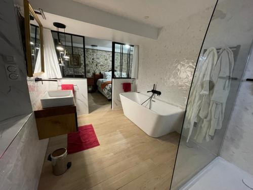 La salle de bains est pourvue d'une baignoire, d'un lavabo et d'un miroir. dans l'établissement La demeure de Liers, à Sainte-Geneviève-des-Bois