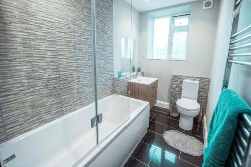 a bathroom with a tub and a toilet and a sink at 4 Bedroom in Finchley Road in London