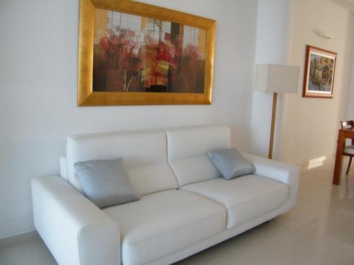 a white couch in a living room with a painting at Villa Floyd Charming Rooms B&B in Pachino
