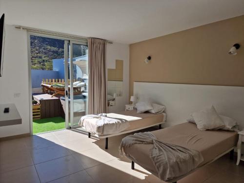 a bedroom with two beds and a balcony at Dúplex de 2 habitaciones y 2 baños y con jackuzzi privado in Tamaimo