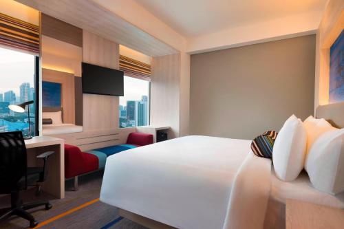 a hotel room with a bed and a desk and a television at Aloft Jakarta Wahid Hasyim in Jakarta