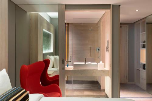 a bathroom with a sink and a red chair at Aloft Jakarta Wahid Hasyim in Jakarta