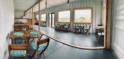 una habitación vacía con mesas, sillas y ventanas en Glamping Spiritul Zimbrului en Vama Buzăului