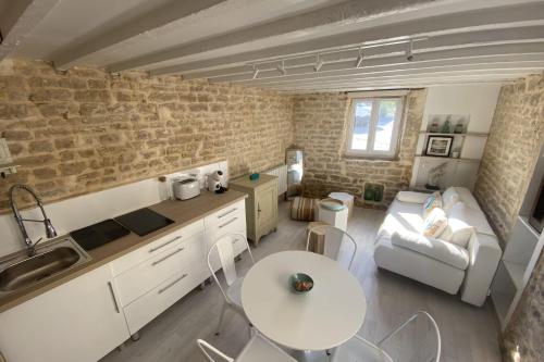 cocina y sala de estar con mesa y sofá en Charming little house with exposed stonework en Luc-sur-Mer