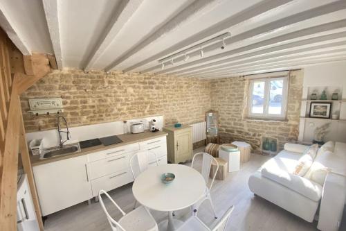 cocina y sala de estar con mesa en Charming little house with exposed stonework en Luc-sur-Mer