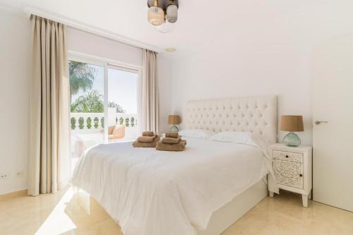 a white bedroom with a large bed with two stuffed animals on it at ARCADIA - AVENIDA 28 De LAS ADELFAS 29680 ESTEPONA, MALAGA in Estepona