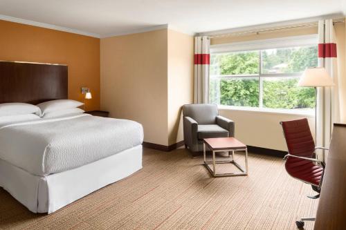 a hotel room with a bed and a chair and a window at Four Points by Sheraton Surrey in Surrey