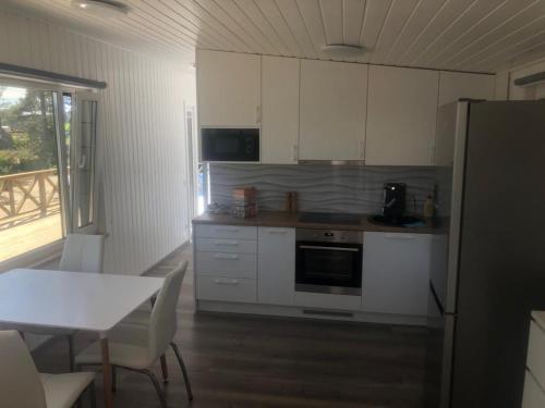 uma cozinha com armários brancos, uma mesa e um frigorífico em Kemping 1 em Föglö