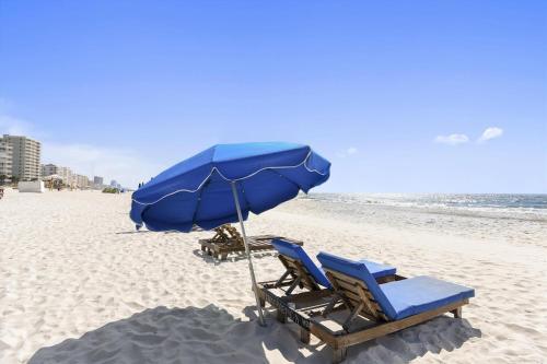 two lounge chairs and an umbrella on a beach at Phoenix 5 Unit 1504 in Orange Beach
