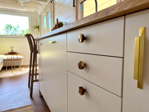 uma cozinha com armários brancos e uma cadeira de madeira em Tiny House Gänseblümchen em Kirchanschöring