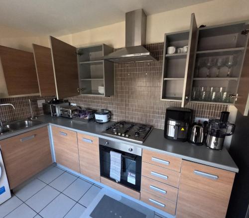 a kitchen with wooden cabinets and a stove top oven at Keniji Luxury 2 Bed Apartment in Milton Keynes