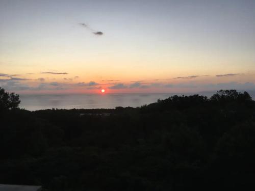 a sunset with the sun in the sky and trees at Masaya Villa - Vacation STAY 23221v in Ito