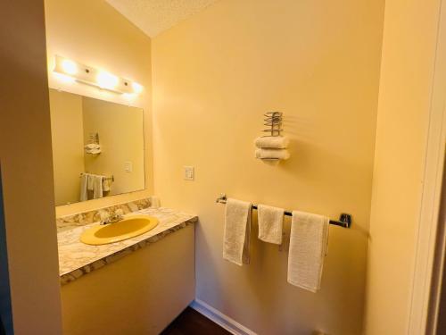 y baño con lavabo, espejo y toallas. en Countryside Inn Lake George, en Lake George