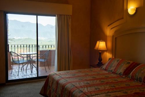 a hotel room with a bed and a view of a balcony at Hotel Hacienda Cola del Caballo in Santiago