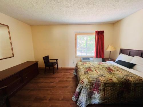 a bedroom with a bed and a desk and a window at Countryside Inn Lake George in Lake George