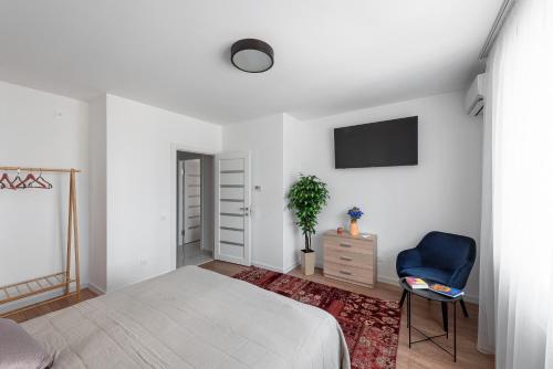 - une chambre blanche avec un lit et une chaise bleue dans l'établissement Luxury Apartment Slava Ukraini, à Ivano-Frankivsk