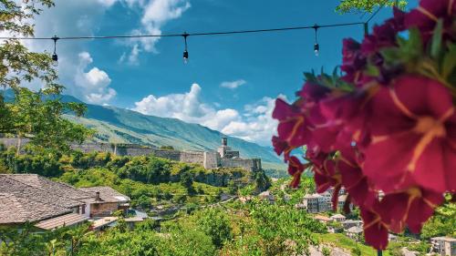 a view of a town with pink flowers at Clockwise GuestRooms in Gjirokastër