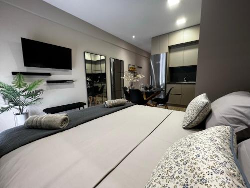 a bedroom with a large white bed with a tv on the wall at Urban Gem by Homebrain in Alexandroupoli