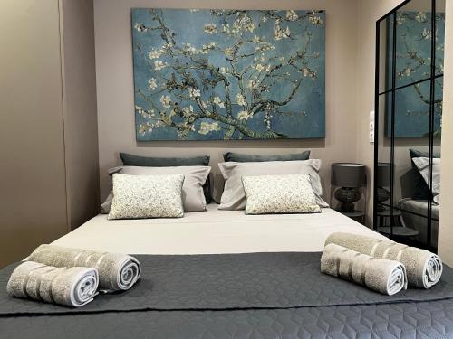 a bedroom with a large bed with pillows and a painting at Urban Gem by Homebrain in Alexandroupoli