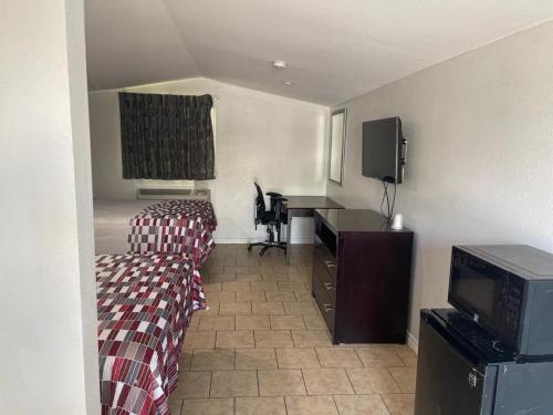コーパスクリスティにあるSafari Inn Motelのベッド、デスク、テレビが備わる客室です。
