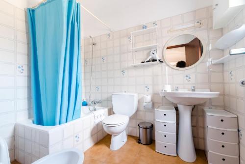 a bathroom with a blue shower curtain and a toilet and sink at Casa Vicent Campanitx Es Pujols in Es Pujols