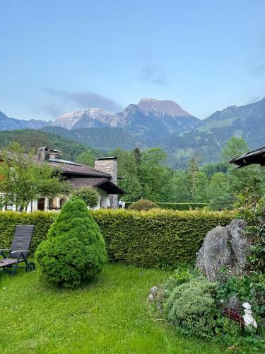a garden with a bench and mountains in the background at Aparthotel Hochfeld in Schönau am Königssee