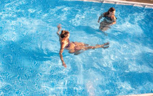 two women are swimming in a swimming pool at Dobre Smaki Apartaments Chill and Food in Sarbinowo