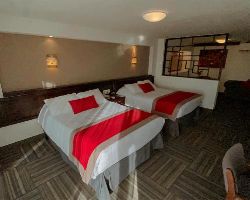 a hotel room with two beds and a mirror at Ramada Plaza by Wyndham Leon in León