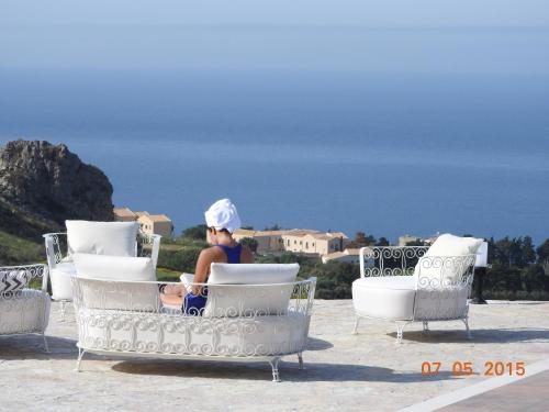 a woman sitting in a chair on a patio at Hotel Antica Cascina Del Golfo in Scopello