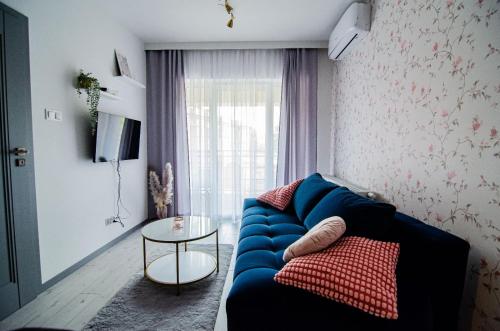 a living room with a blue couch and a table at Apartament KARMEL in Przemyśl