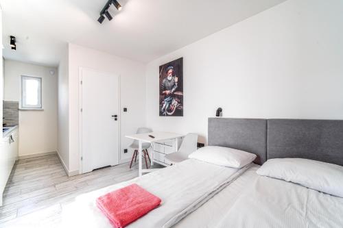 a white bedroom with a bed and a desk at Dobre Smaki Apartaments Chill and Food in Sarbinowo