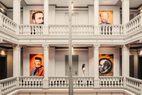 a woman stands in front of portraits on the wall of a museum at The Ritz-Carlton Hotel de la Paix, Geneva in Geneva