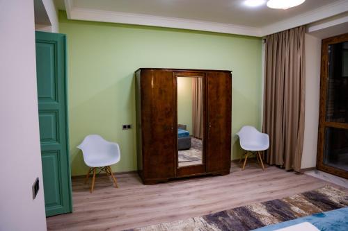 Habitación con 2 sillas blancas y espejo. en Kumayri Suite Balcony View, en Gyumri