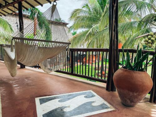 a porch with a hammock and a vase with a plant at El Sitio de Playa Venao in Playa Venao
